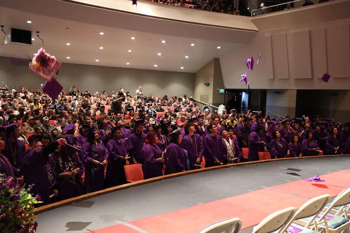 Ace Center graduating class in full gowns throwing caps