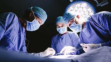 Three people performing surgical procedure.