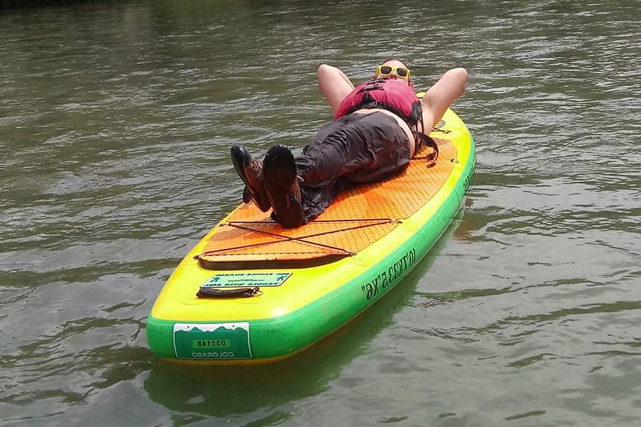 Individual laying on paddleboard floating on water